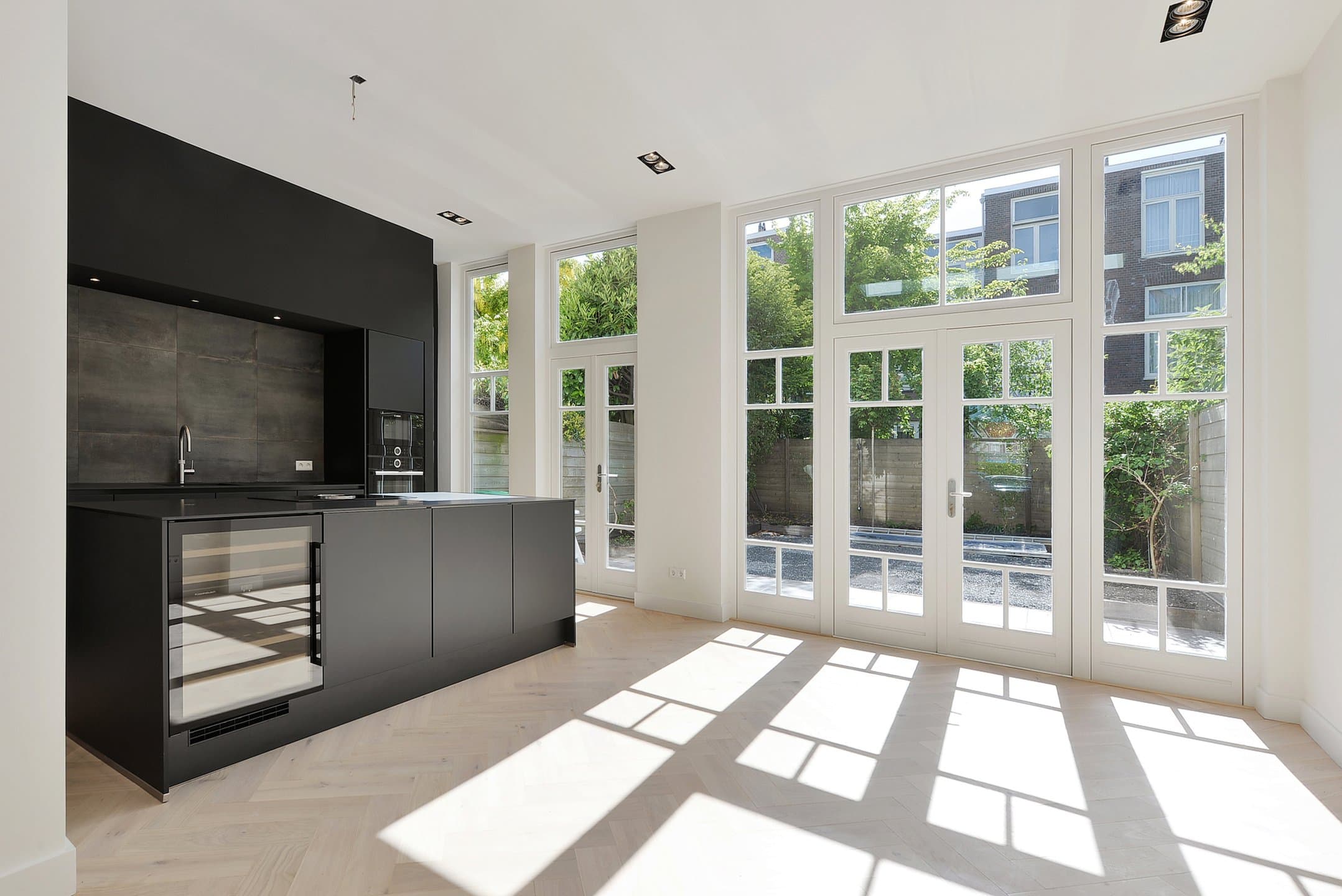 Gerenoveerd herenhuis in Den Haag: open keuken in zwart met tuindeuren